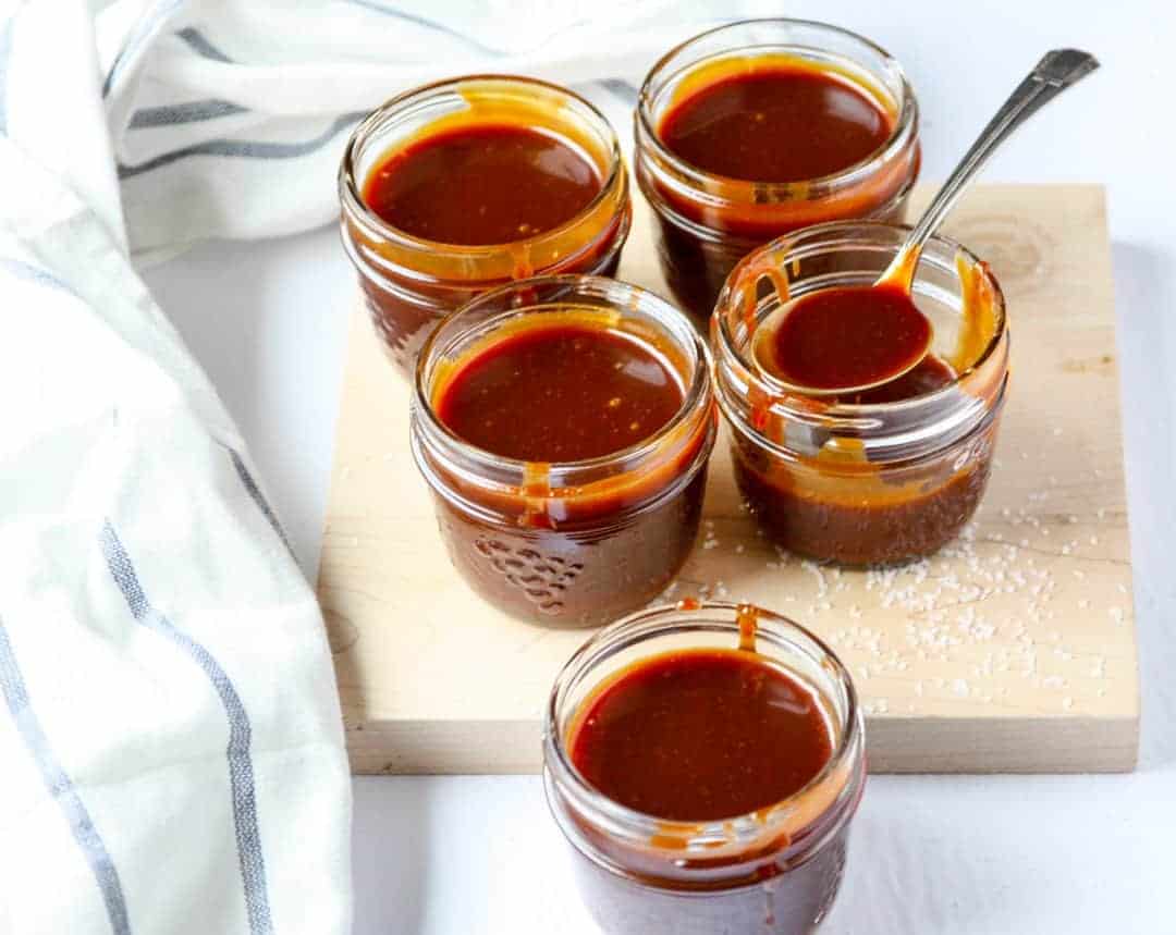 Jars of caramel sauce in glass jars on a cutting board