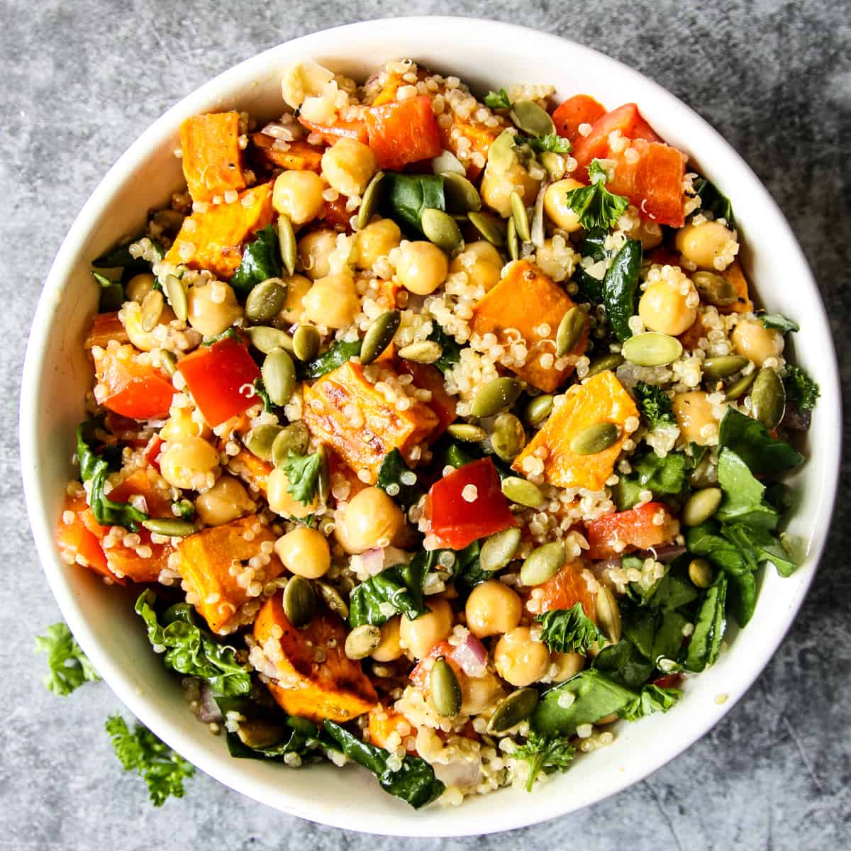 Sweet potato quinoa salad with chickpeas and spinach in a white bowl.