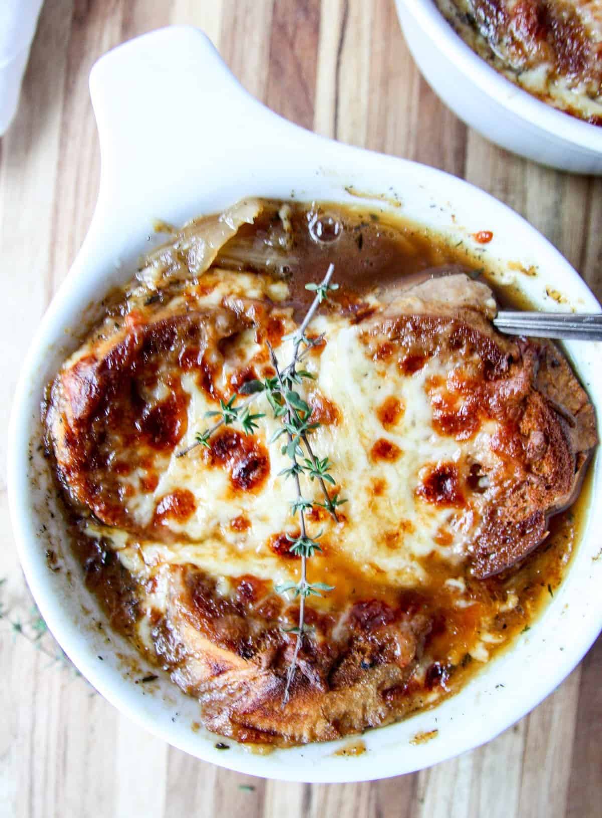 French onion soup in a white bowl with a spoon.