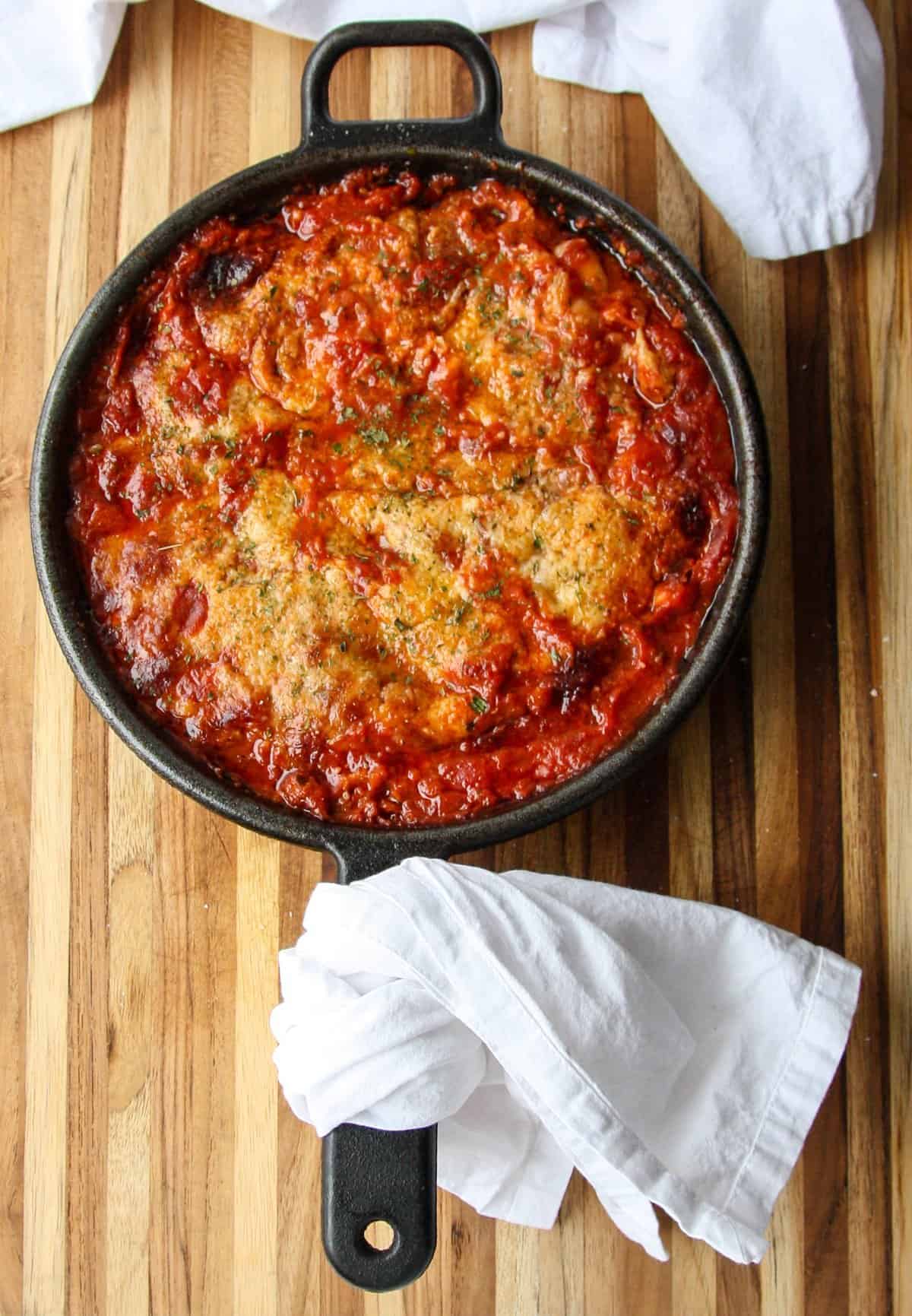 A pan of baked chicken covered in tomato sauce and cheese.