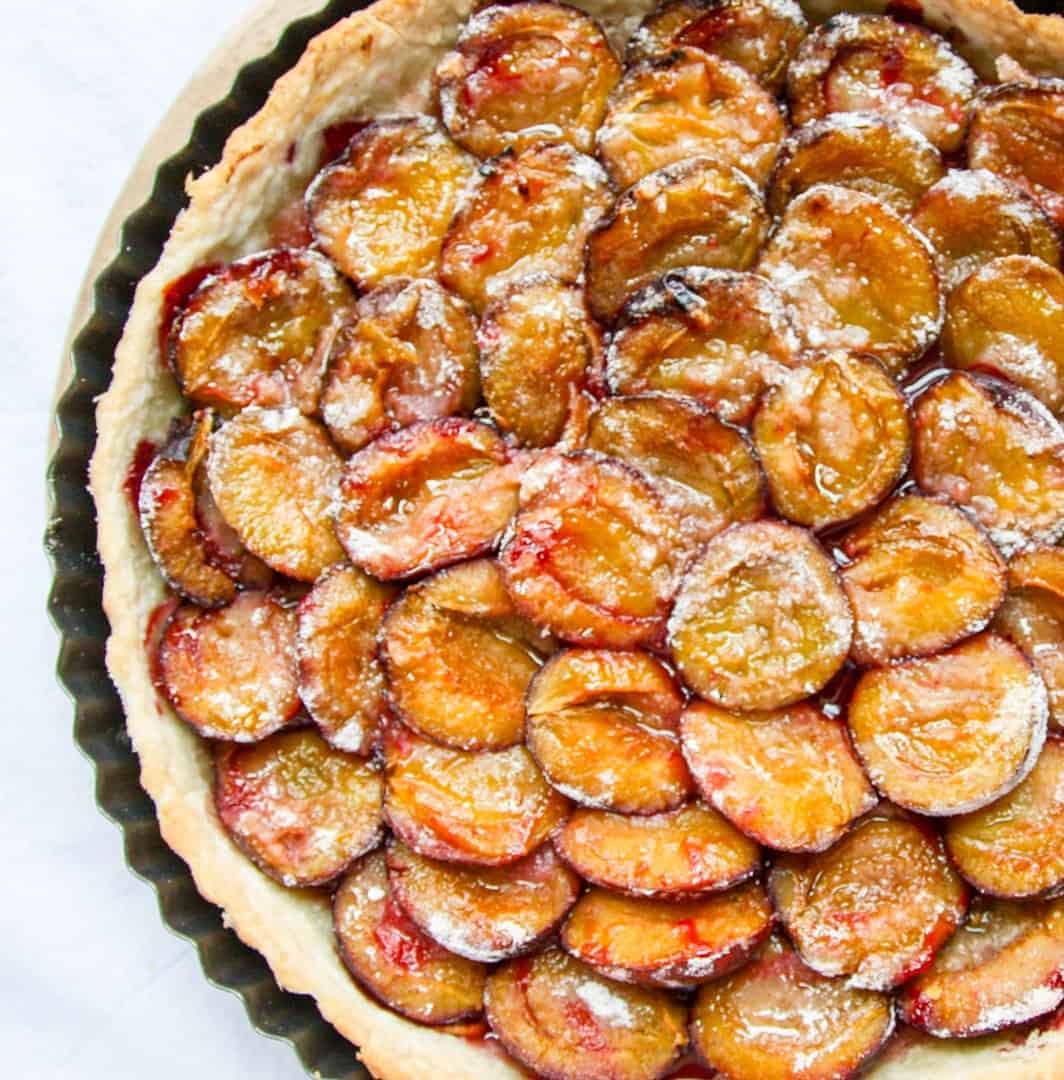 A close up of a baked plum tart in a pan