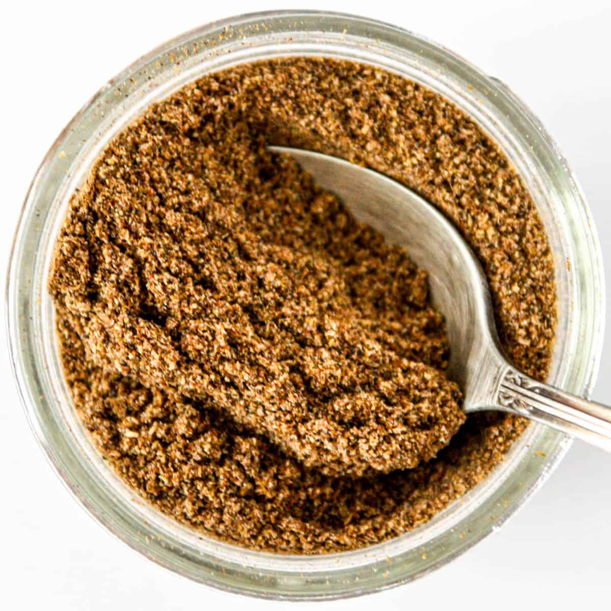 A small glass jar of homemade garam masala spice blend.