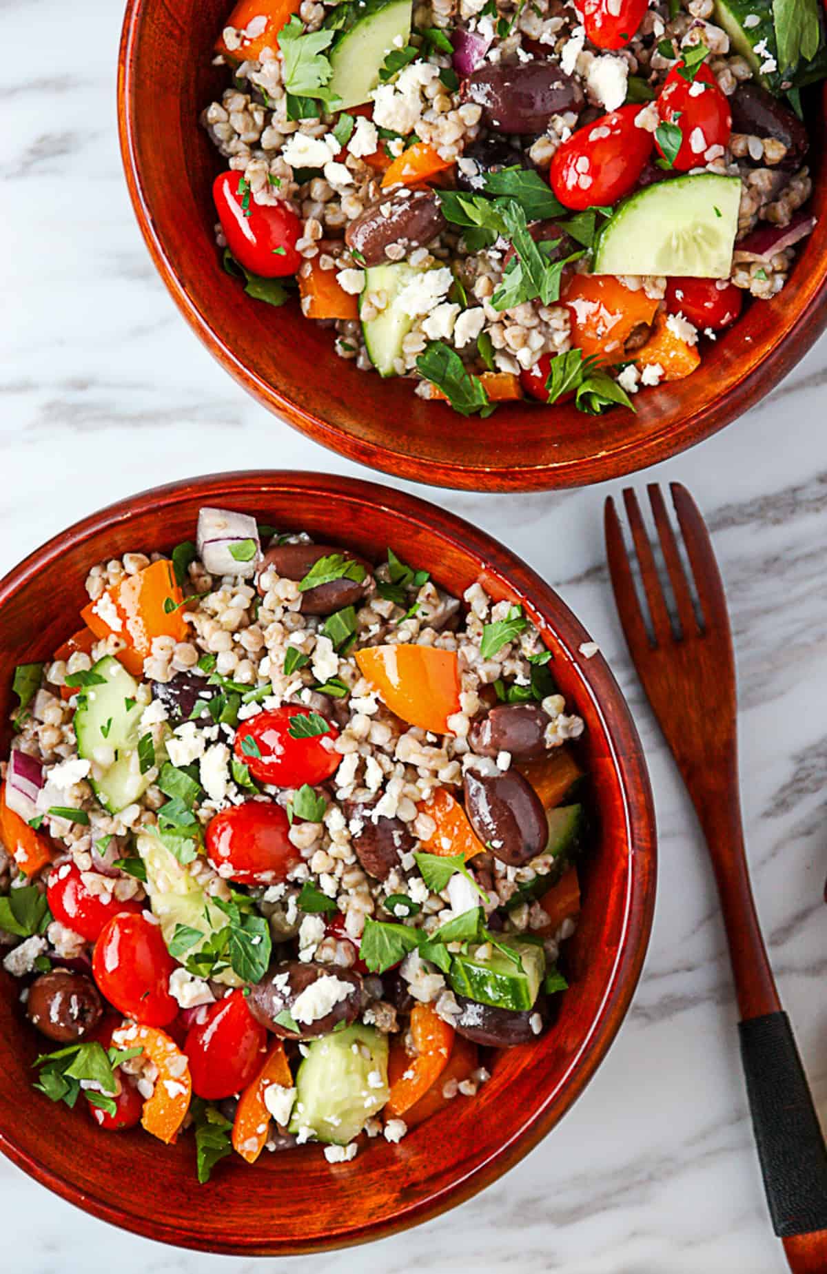 Two bowls of buckwheat salad with a salad fork.
