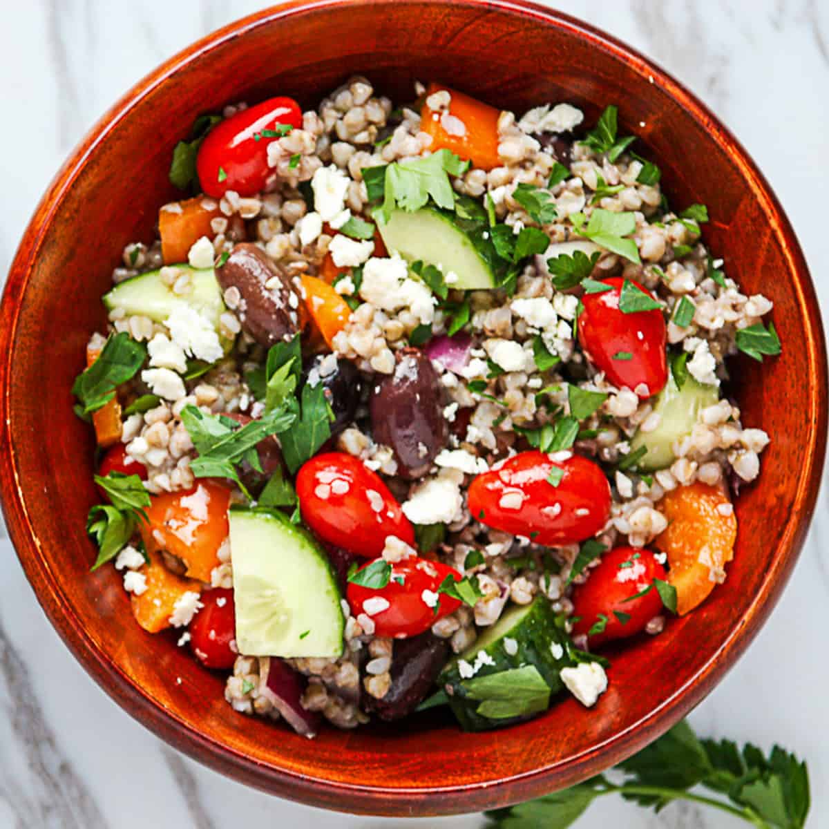 Mediterranean buckwheat salad in a dark wood salad bowl.