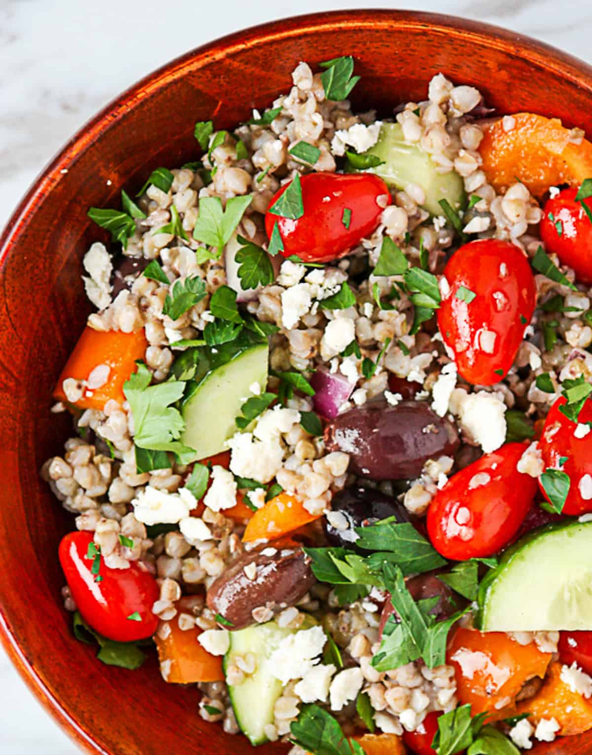 Mediterranean buckwheat salad in a dark wooden bowl.