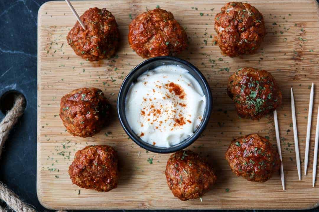 Eight Cajun Turkey Meatballs on a wooden platter with a dish of ranch dip