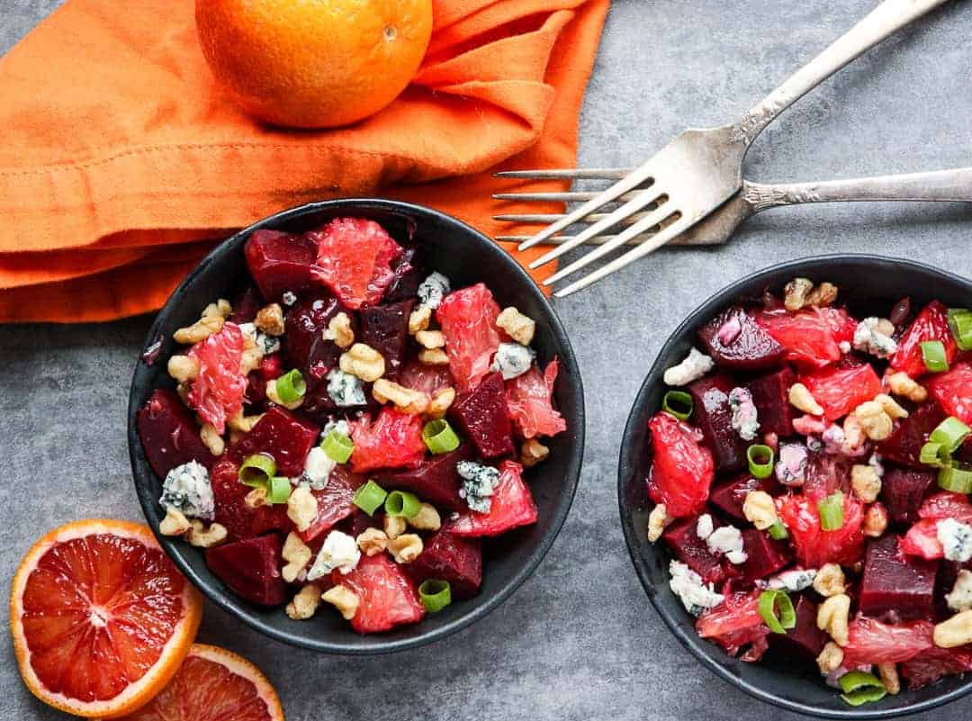 Beet salad with grapefruit slices and blue cheese crumbles in black bowls