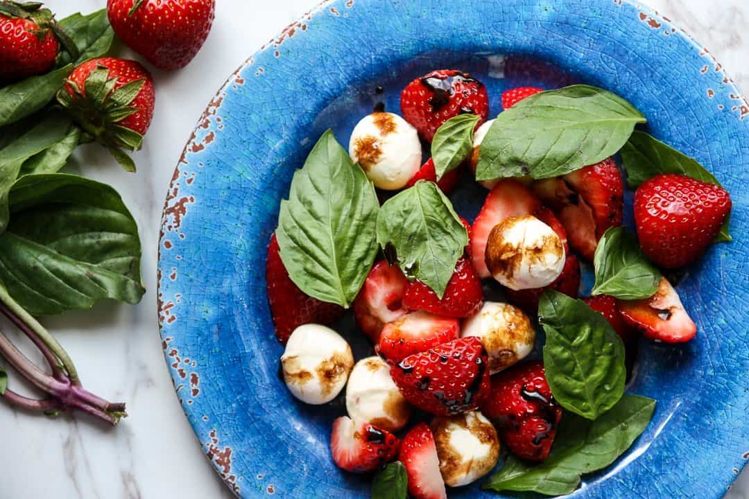 Top shot of strawberry caprese salad on blue plate.