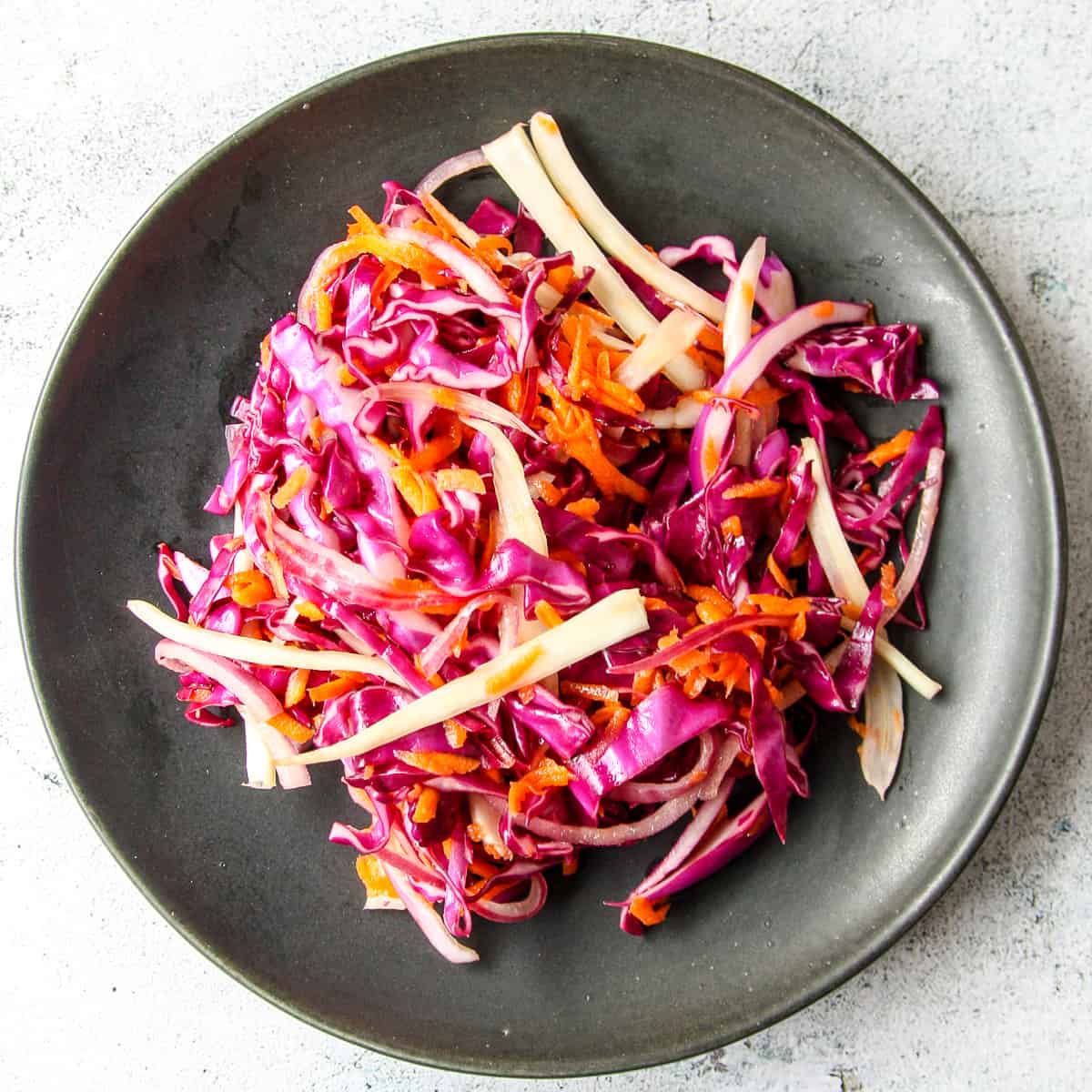 Red cabbage slaw on a black plate.