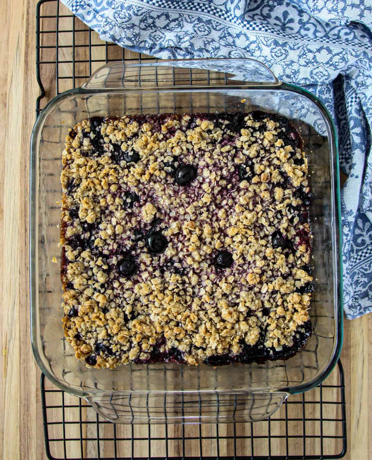 The pan of baked blueberry oatmeal bars cooling on a wire rack.