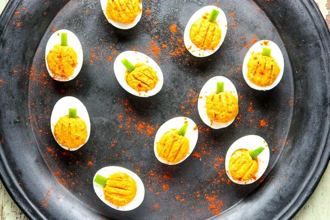 Pumpkin shaped deviled eggs on a black plate