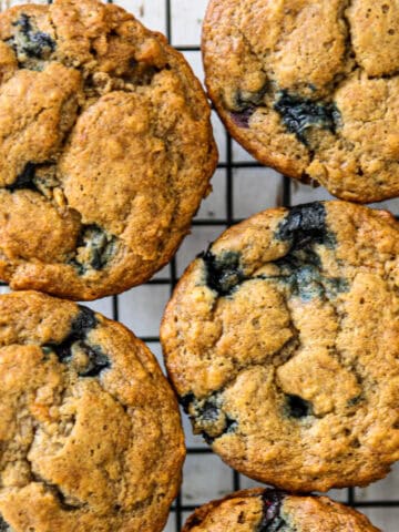 Four banana blueberry muffins on a wire rack.
