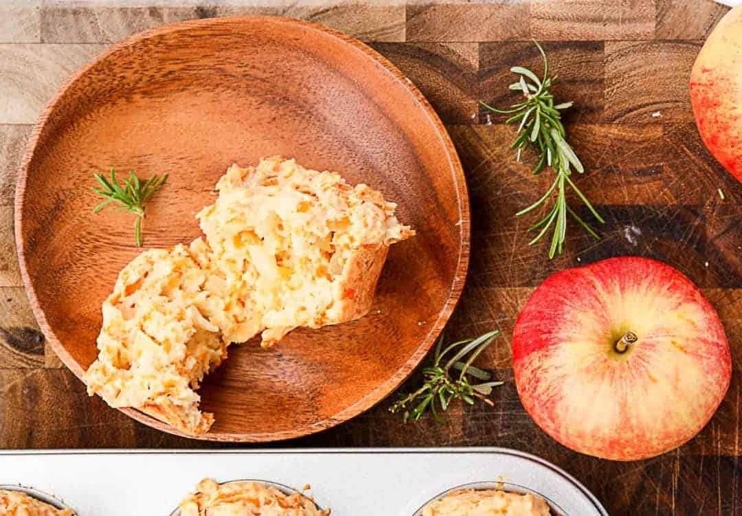 A muffin on a wooden plate with an apple