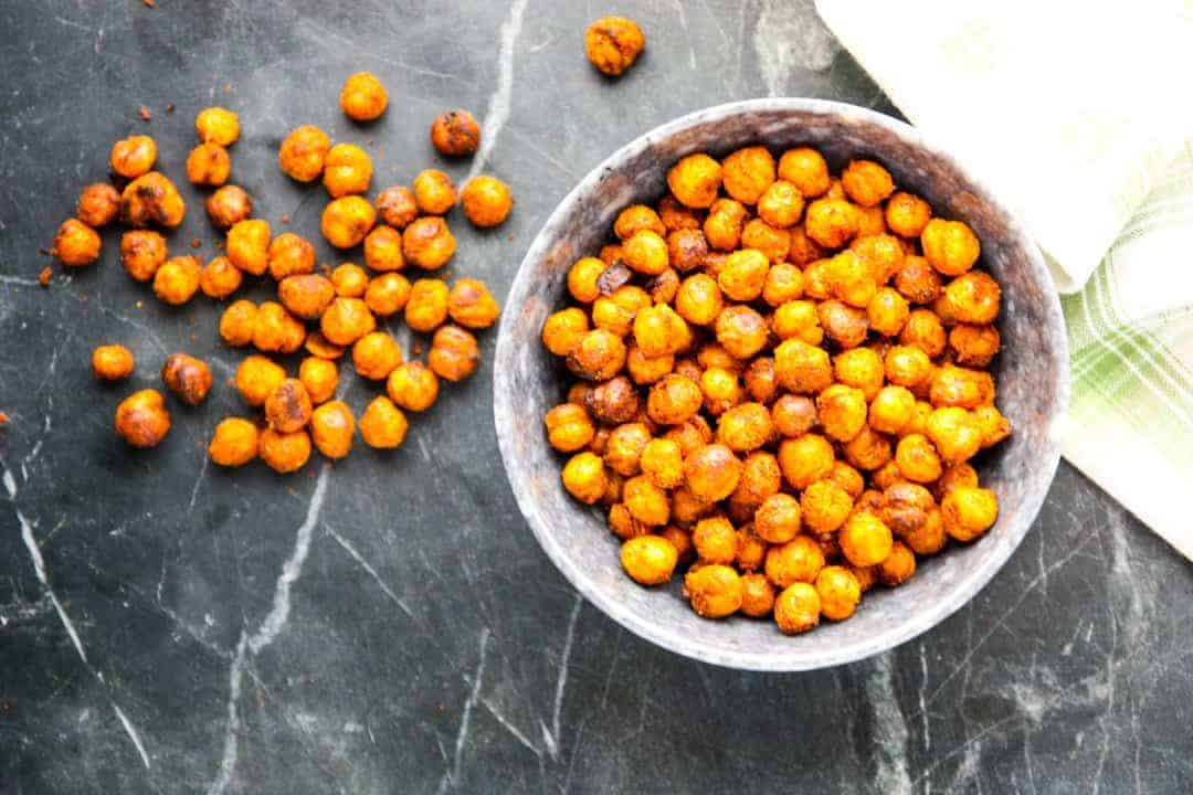 Gray speckled bowl of lemon roasted chickpeas on a black marble countertop