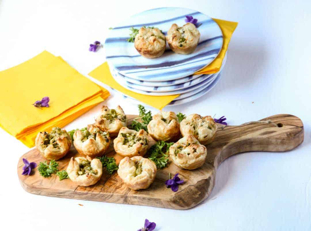 Asparagus puff pastry appetizers on a wooden serving board.