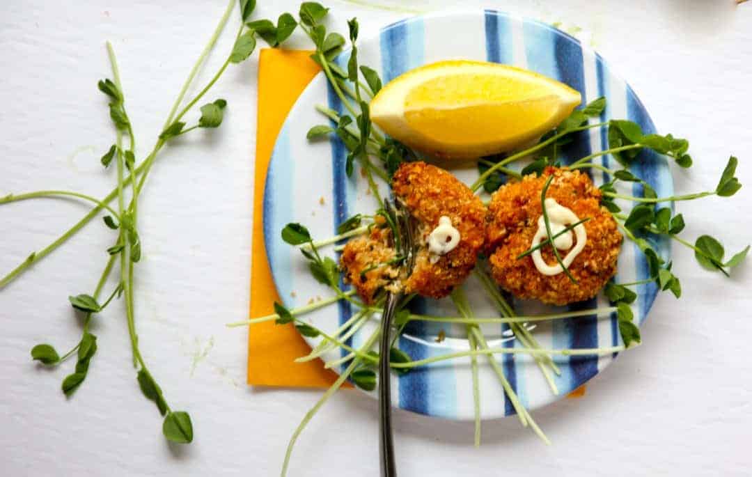 A plate of food on a table, with Crab cakes and lemon wedge