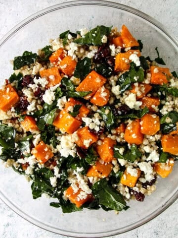 Butternut squash salad with feta, buckwheat and kale, in a glass bowl.