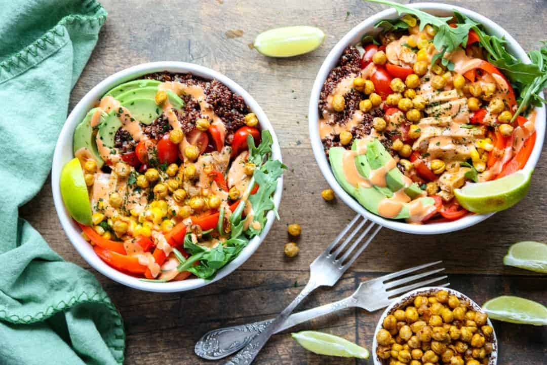 Two white bowls filled with burrito ingredients on wooden table