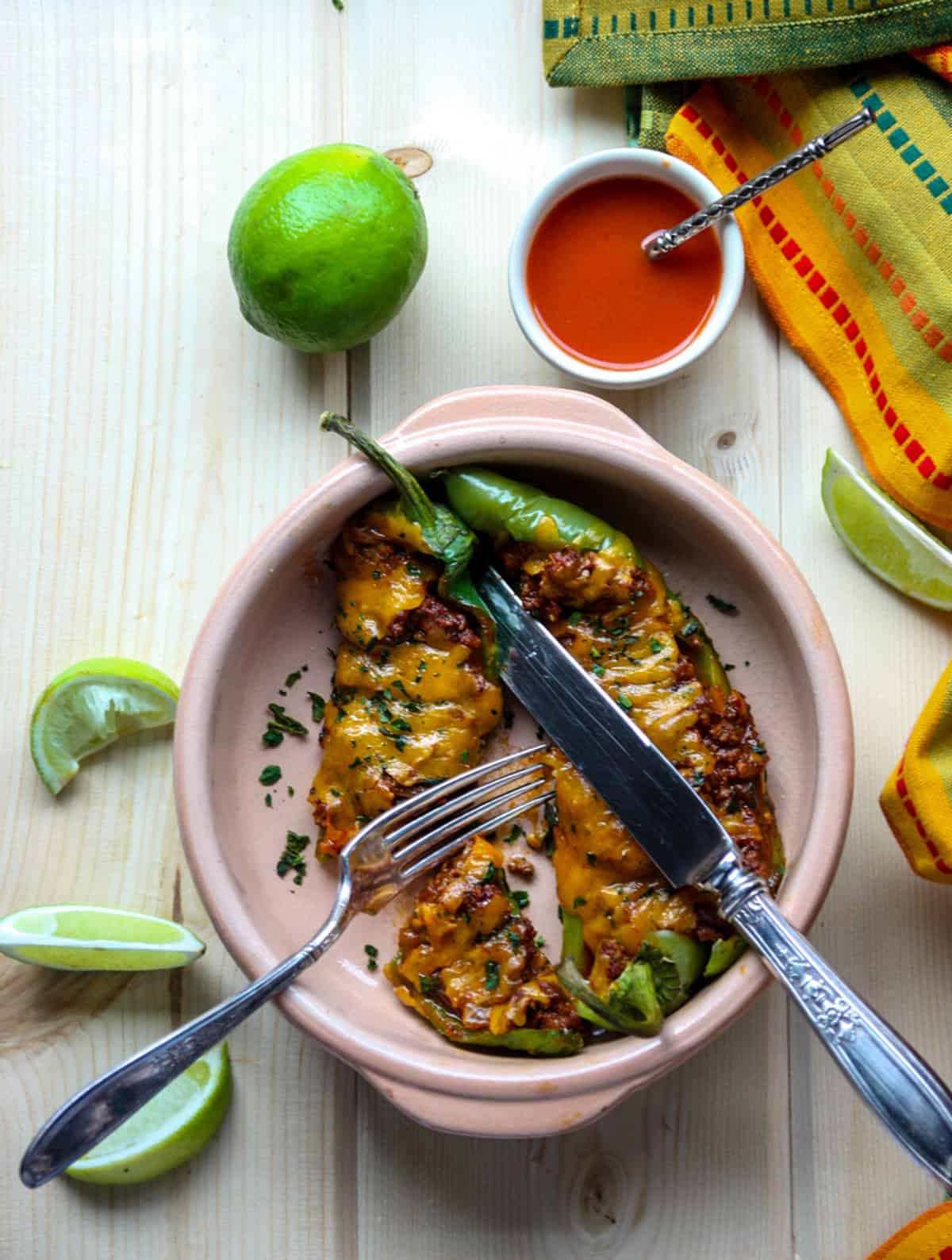 Stuffed Anaheim peppers on a plate surrounded by lime wedges.