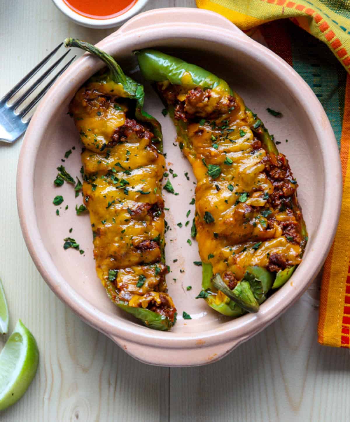 Two beef and cheese stuffed Anaheim peppers in a dish.