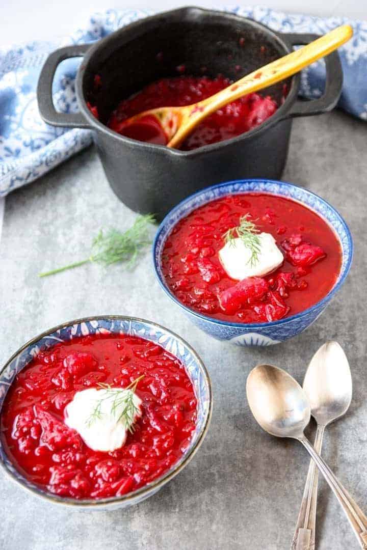 black pot and two blue and white bowls filled with Ukrainian borscht 