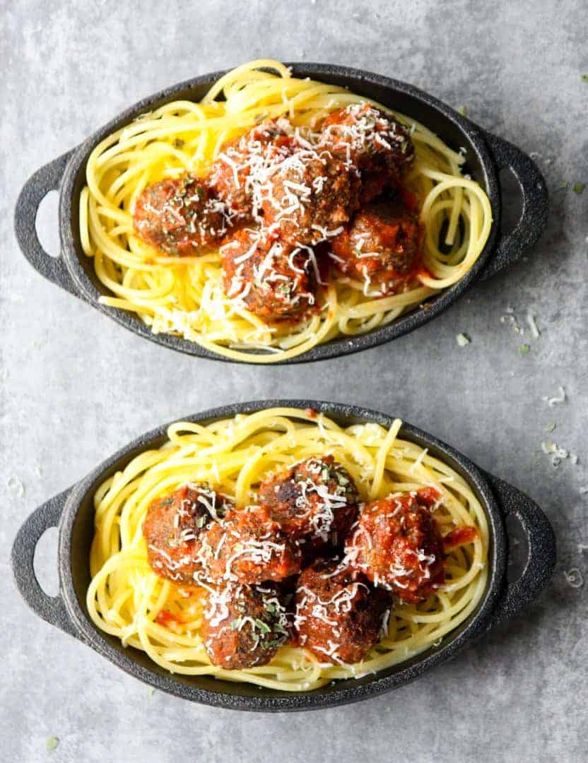 Top shot of two small black skillets with spaghetti and meatballs