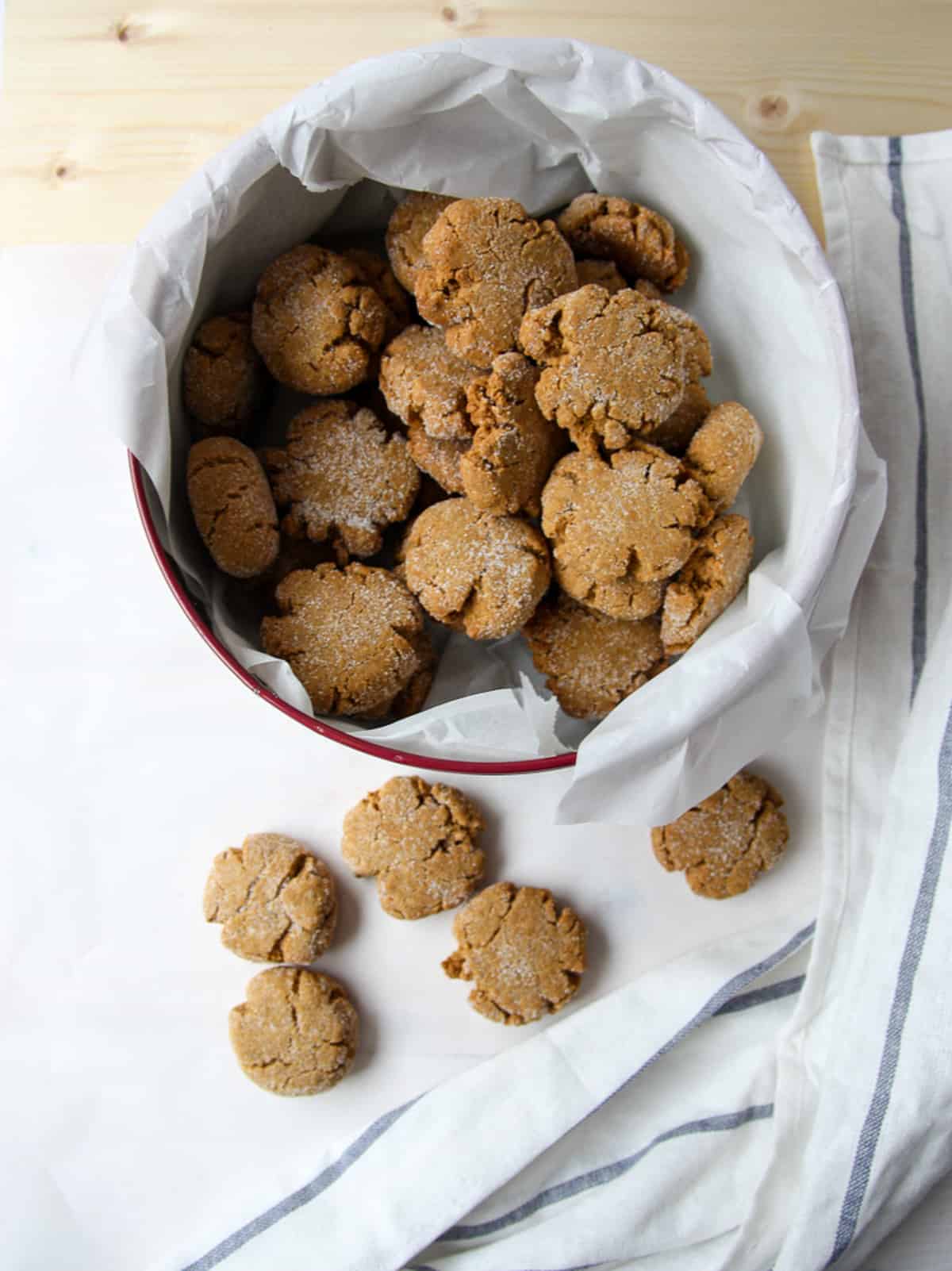 Molasses crinkle cookies in a wax paper lined cookie tin.