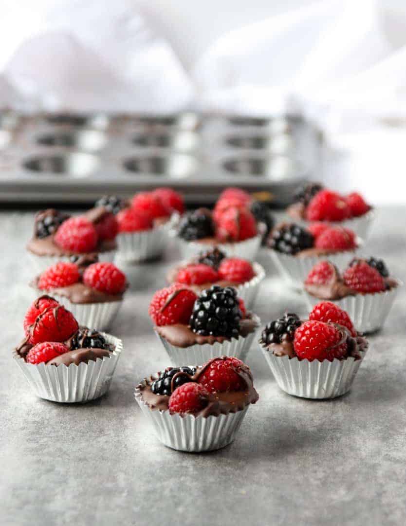 A close up of decorated homemade chocolates topped with berries on a table