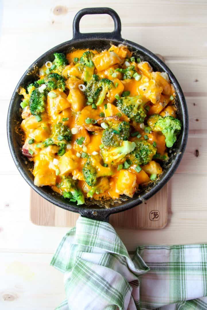 Cheese, broccoli, and potato casserole in black skillet.