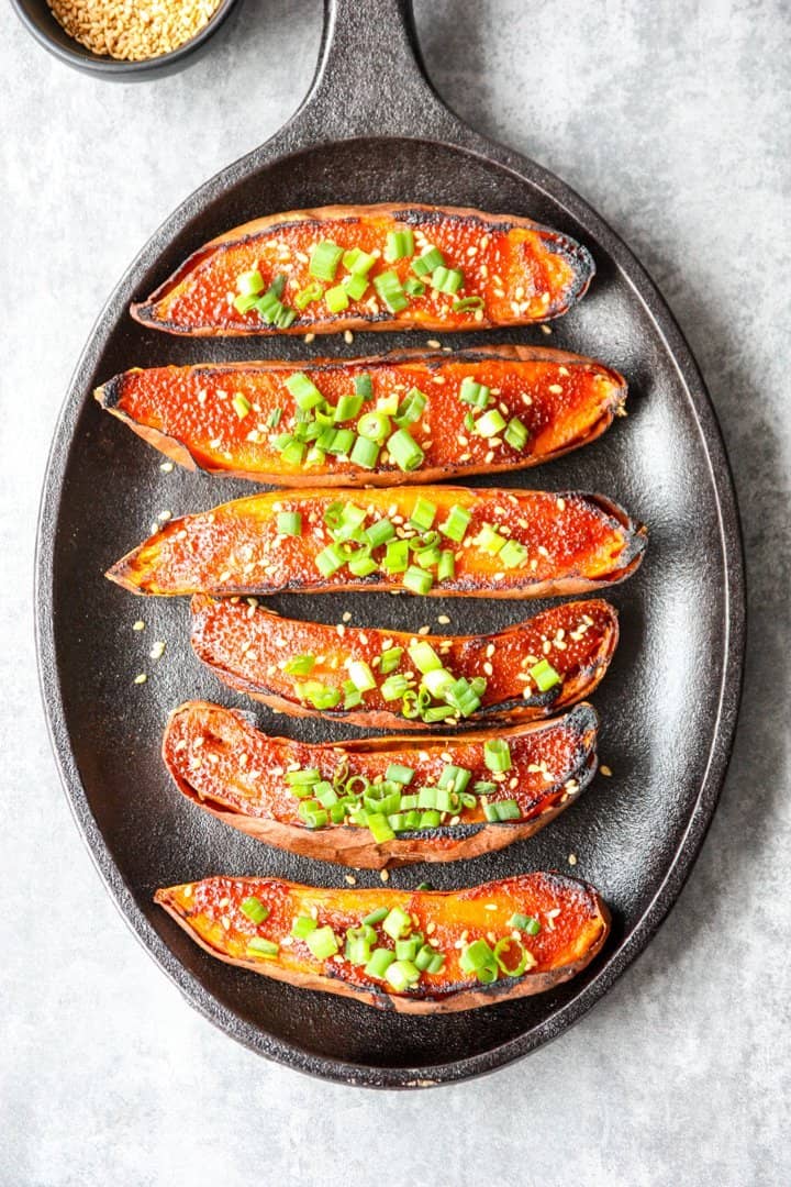six miso baked sweet potato halves on a black cast iron skillet