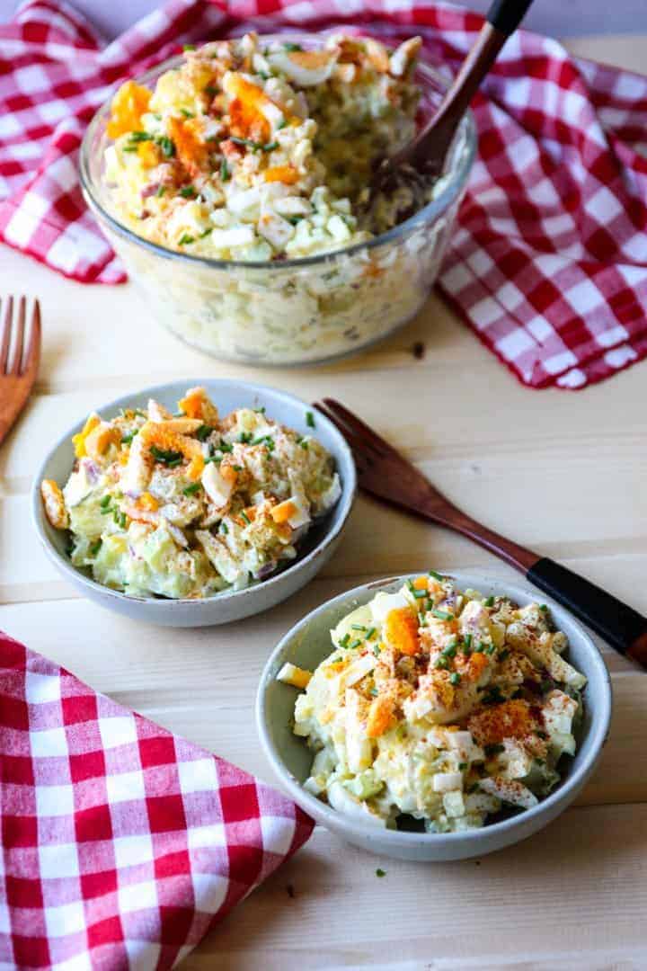 A bowl of salad with two dishes of salad on a table