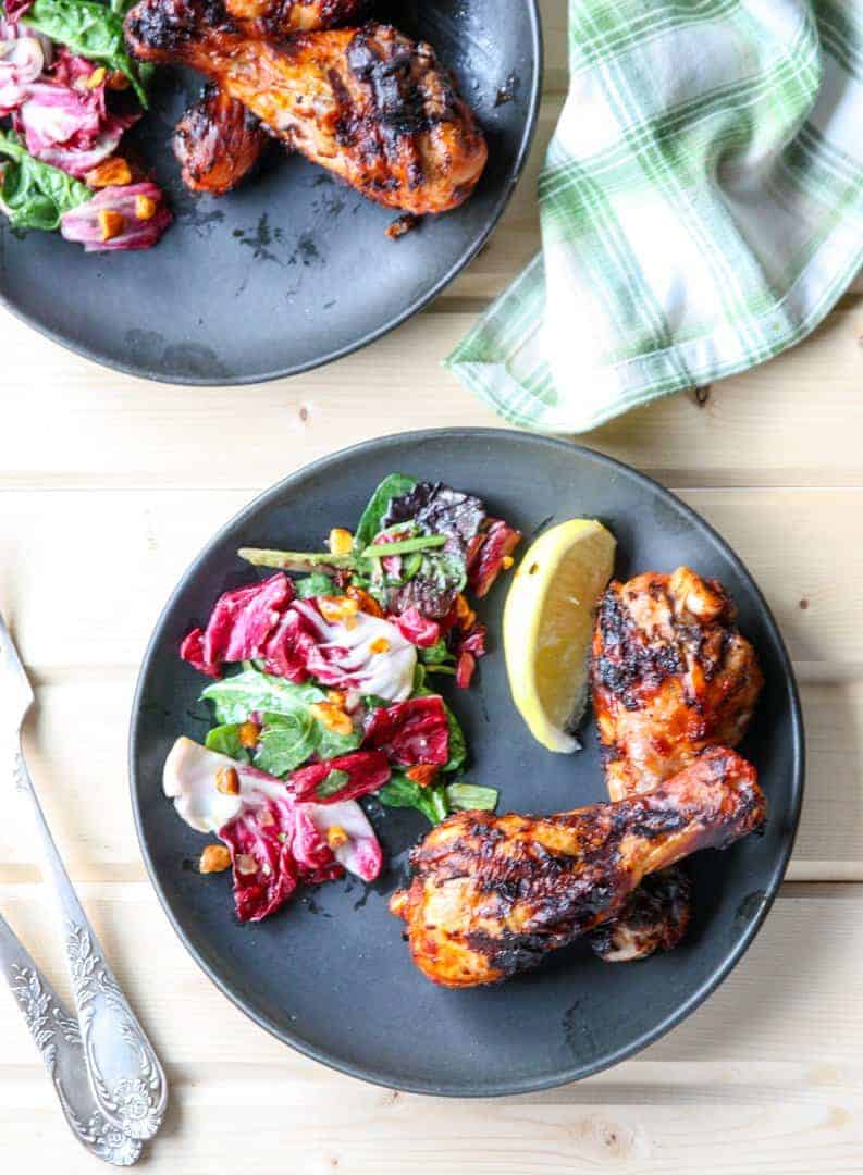 A plate of grilled chicken drumticks on a table