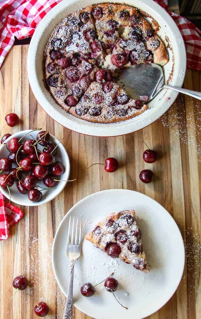 top shot of Cherry Almond Clafoutis on wooden table next to cherries