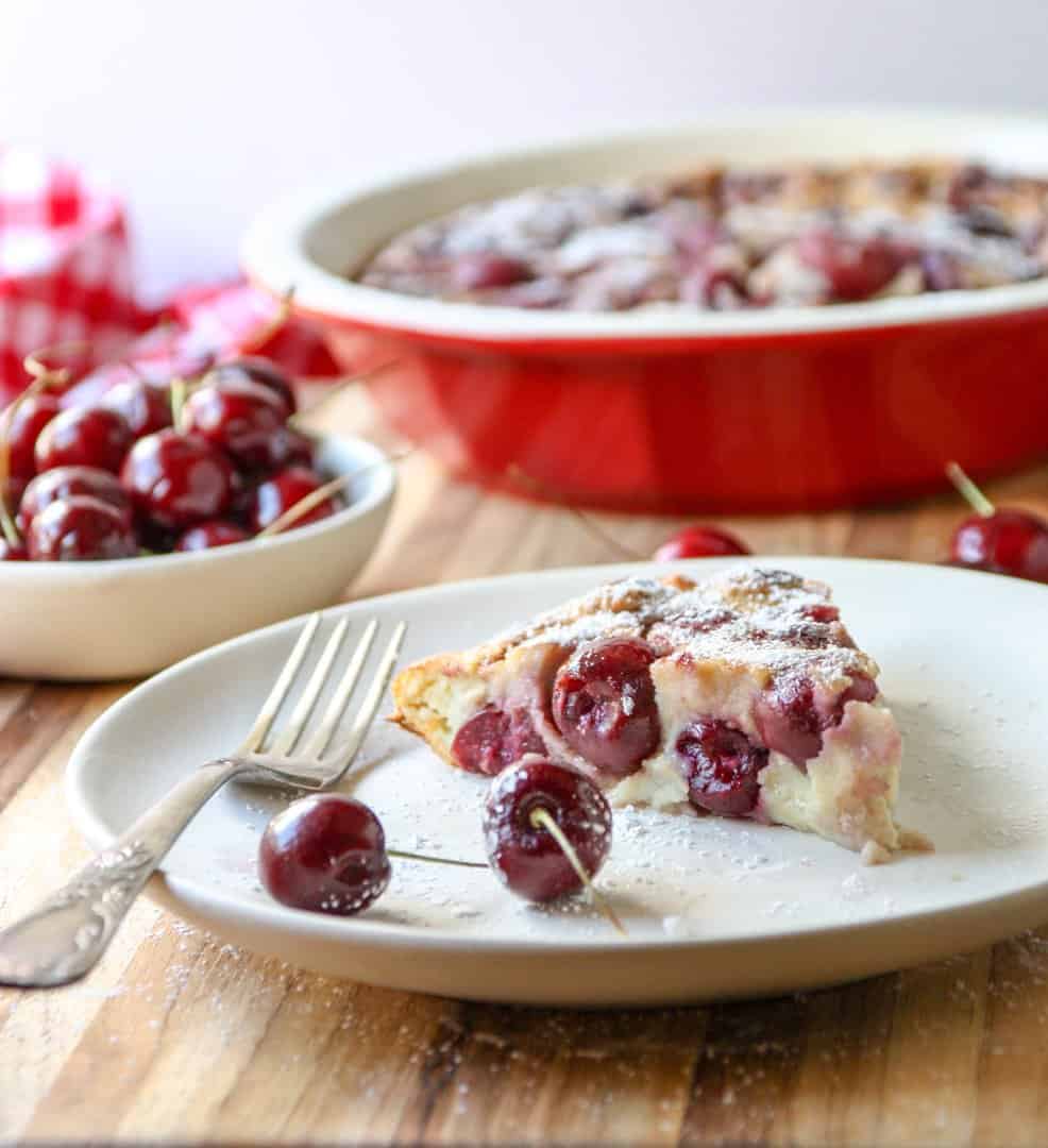 slice of fruit dessert in baking dish on white plate sprinkled with powdered sugar