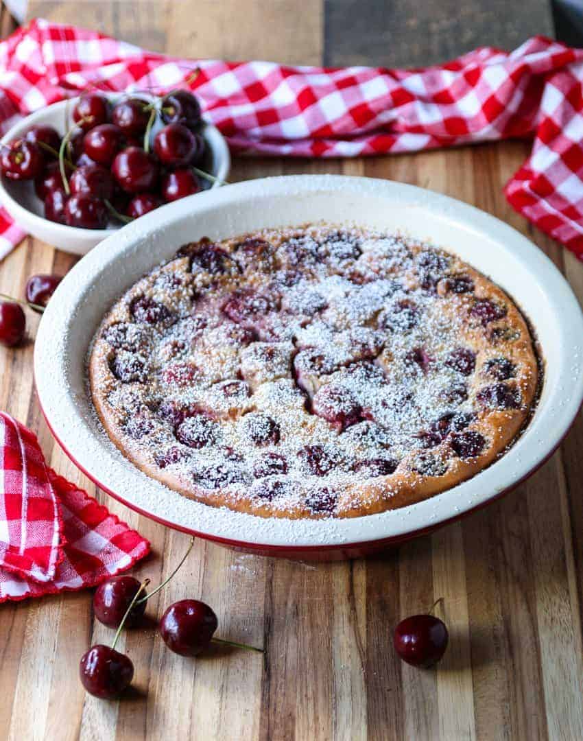 top shot of Cherry Almond Clafoutis on wooden table next to cherries