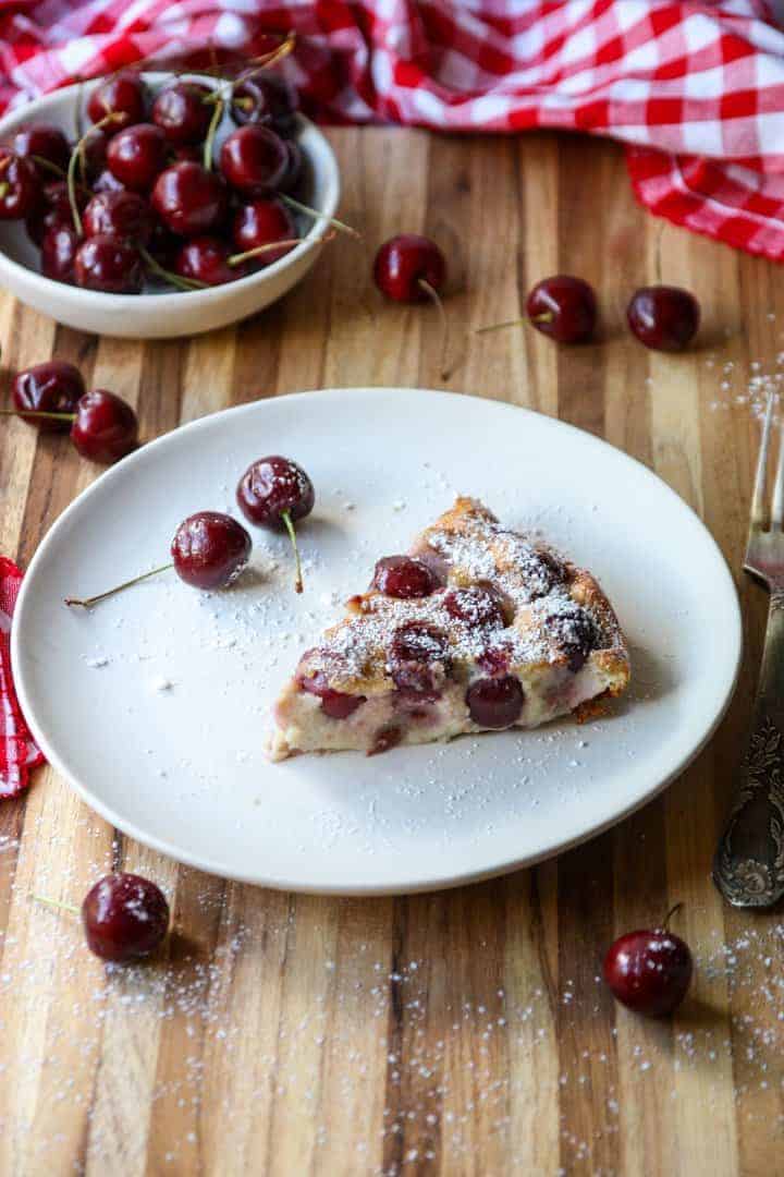 slice of fruit dessert in baking dish on white plate sprinkled with powdered sugar