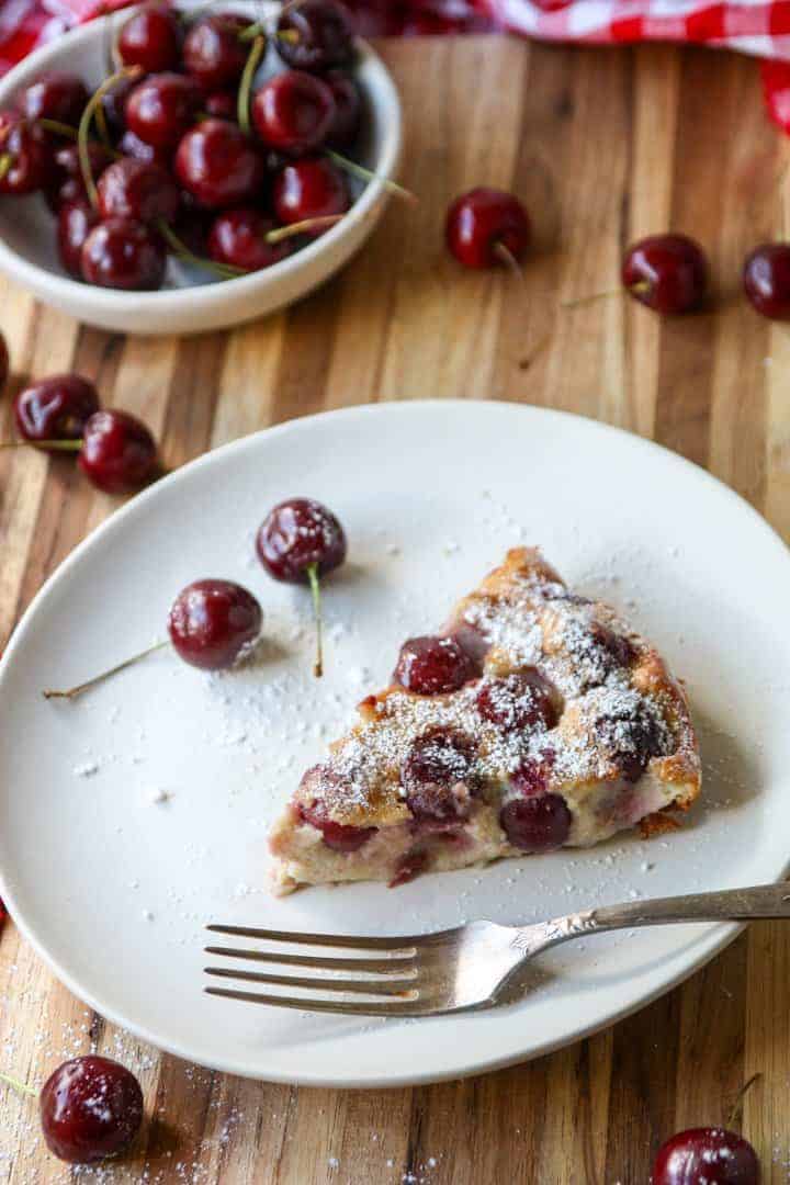 slice of fruit dessert in baking dish on white plate sprinkled with powdered sugar