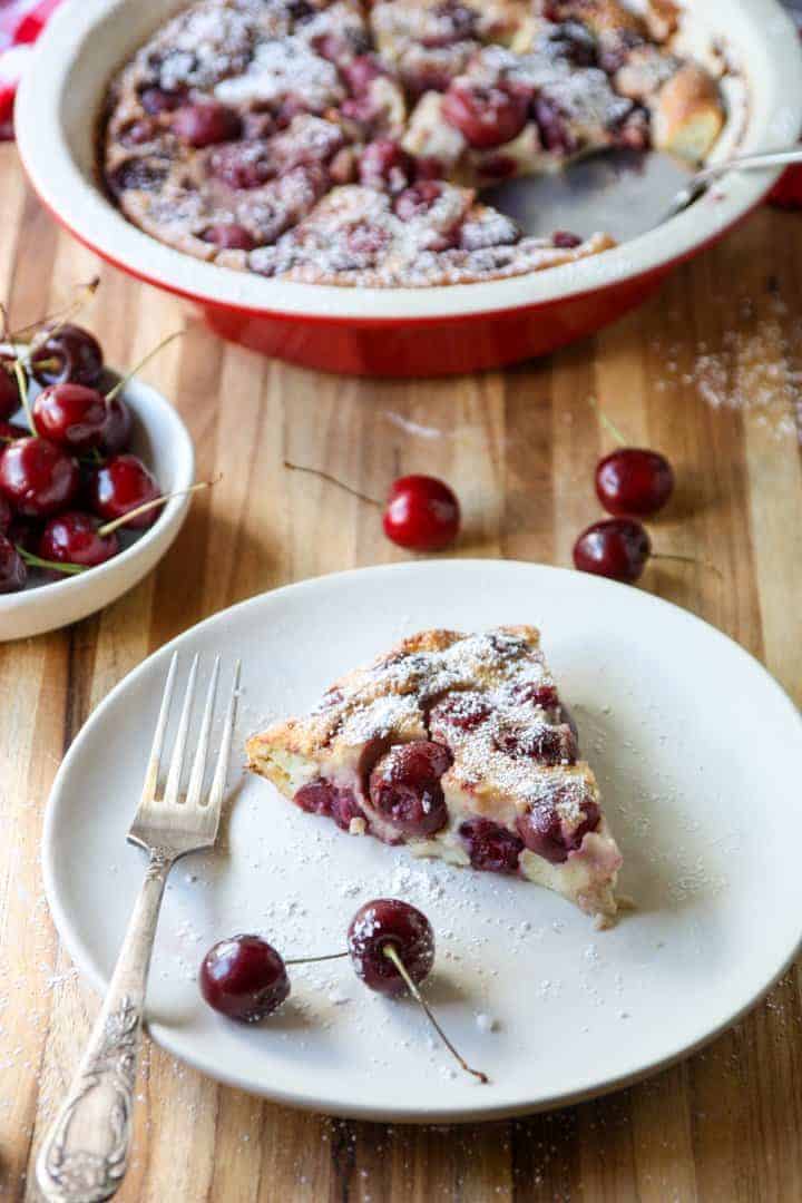 slice of fruit dessert in baking dish on white plate sprinkled with powdered sugar