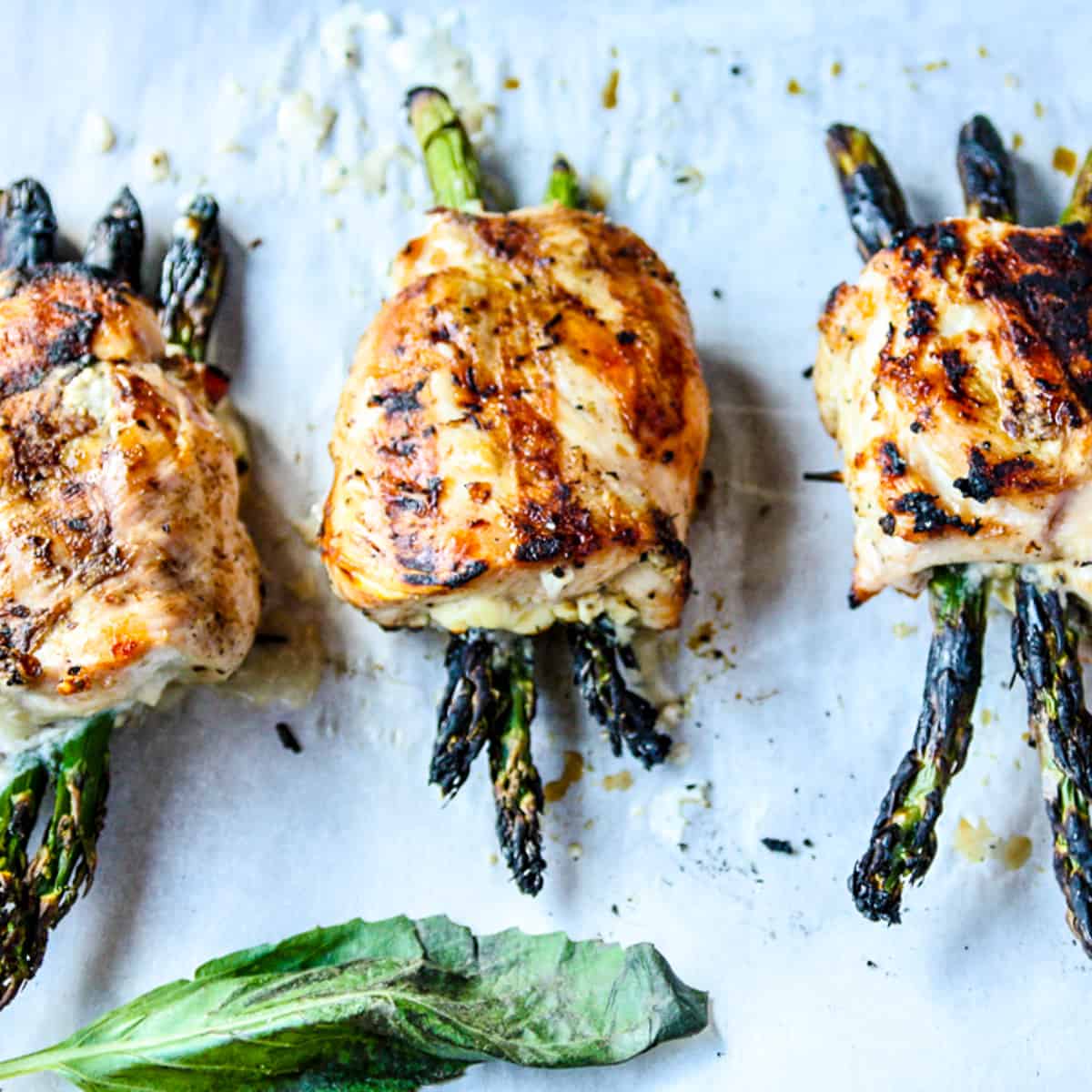 Three grilled asparagus stuffed chicken breasts on a tray.
