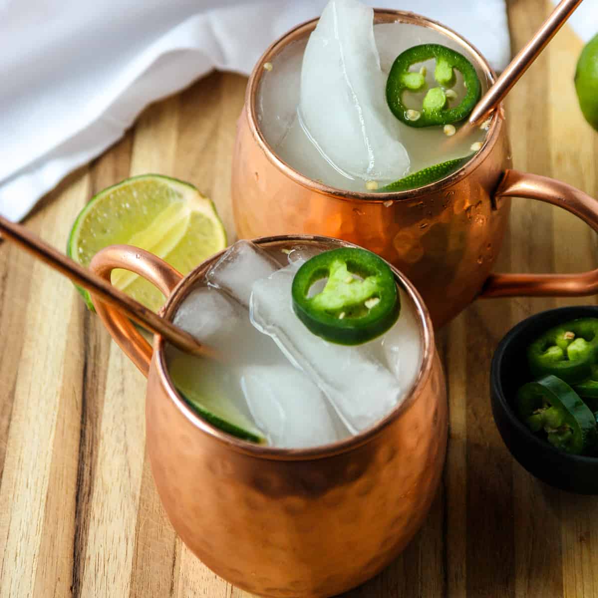 Two Mexican Mule cocktails in copper mugs garnished with lime.