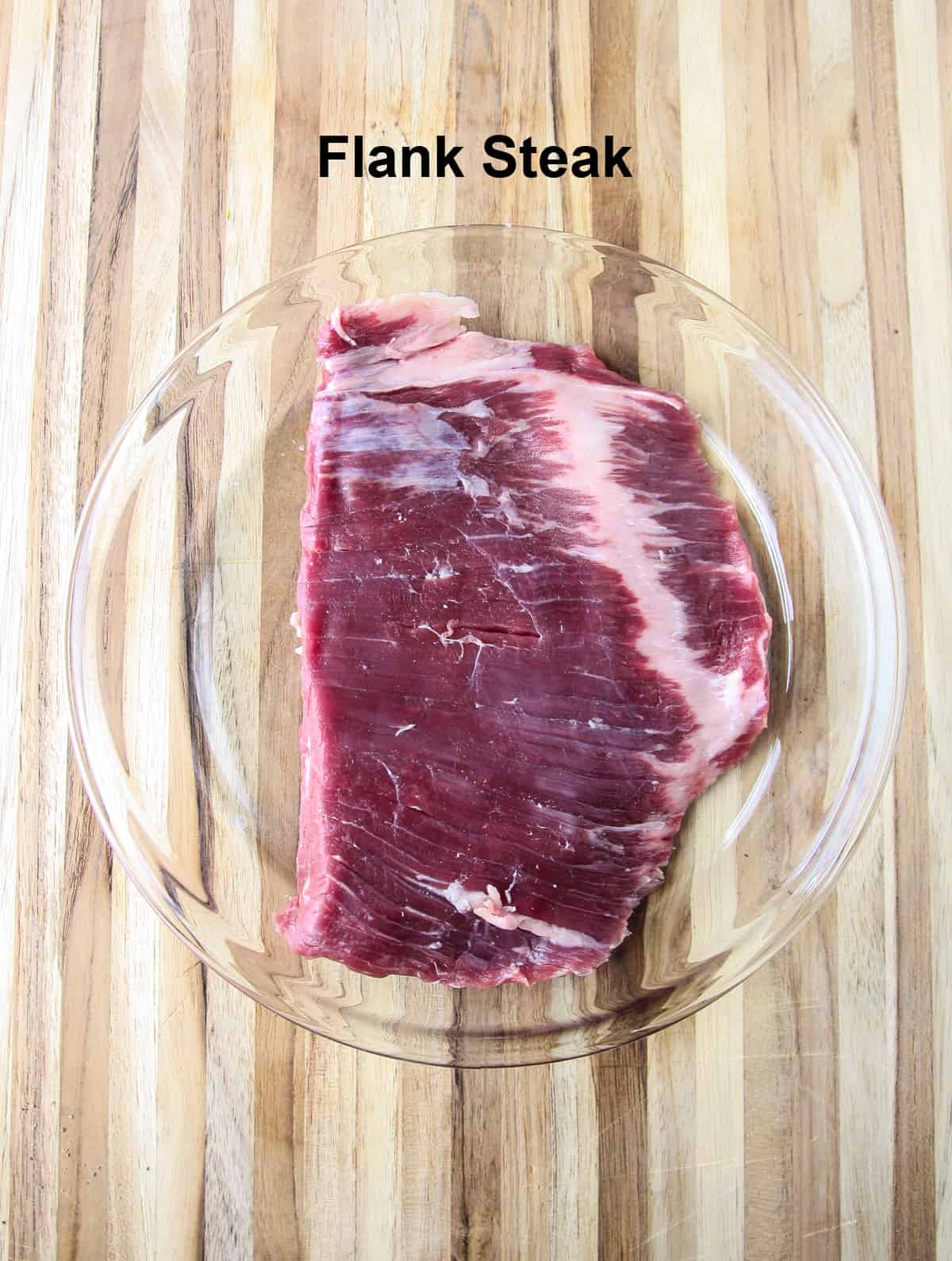 A raw flank steak on a glass plate.