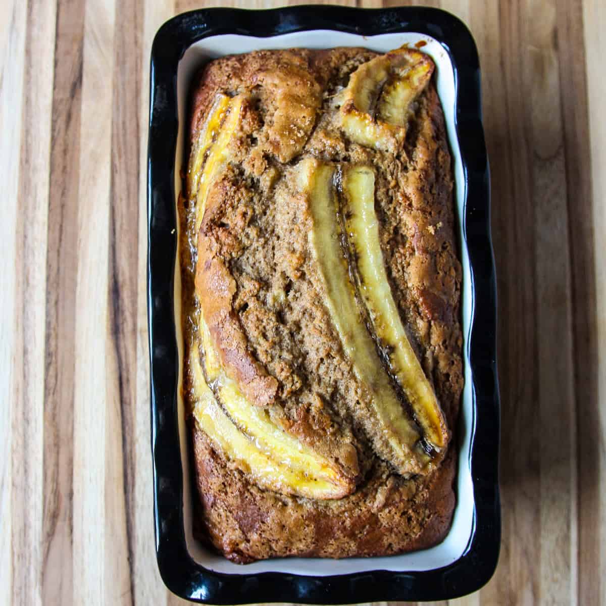 A baked loaf of buckwheat banana bread in a black & white pan.