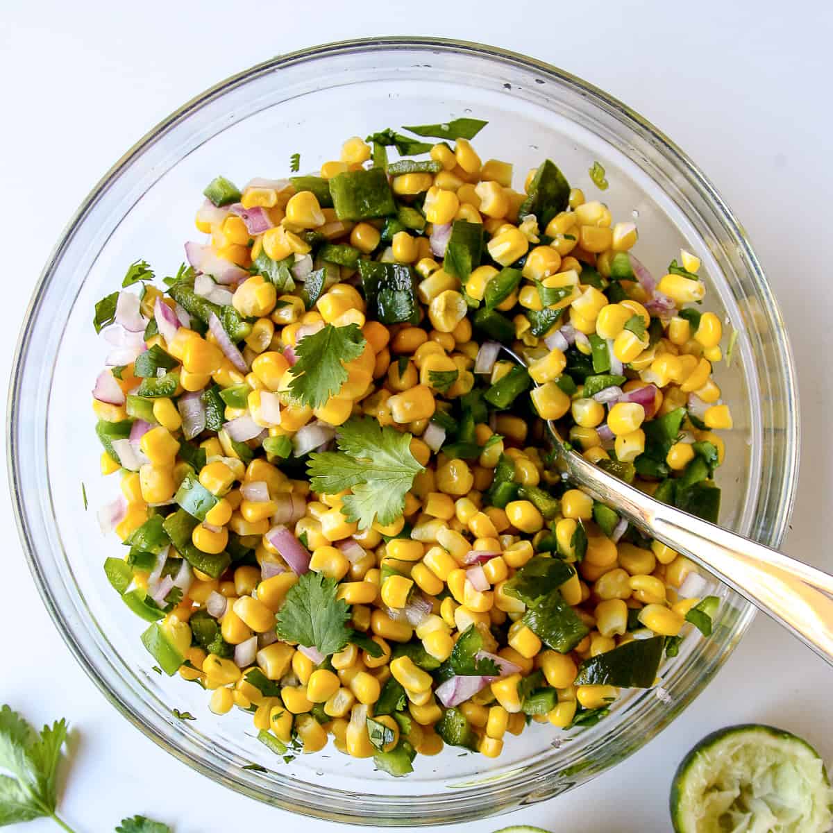 Roasted chili corn salsa in a glass bowl with a spoon.