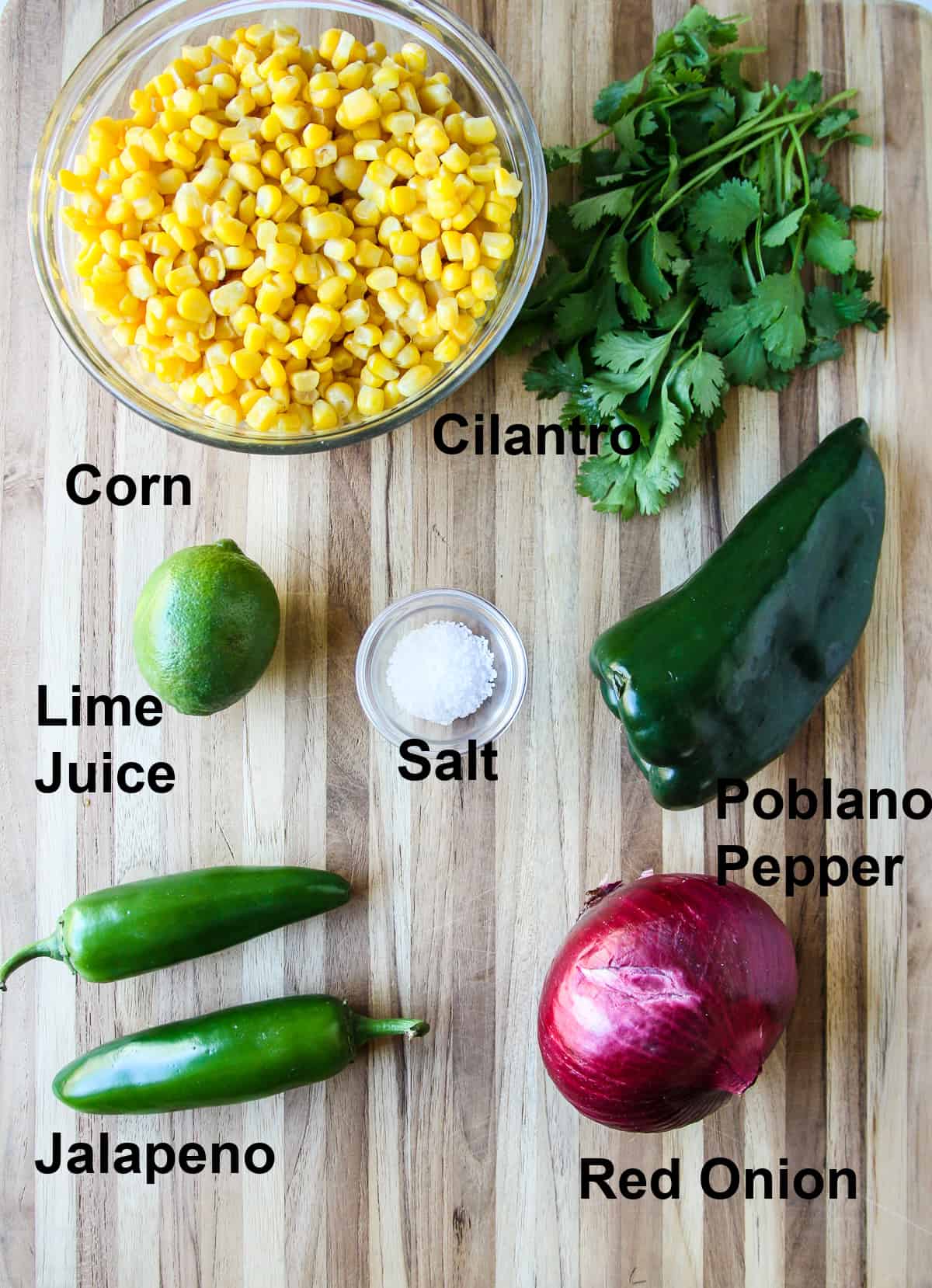 All of the ingredients to make the corn salsa on a wooden board.