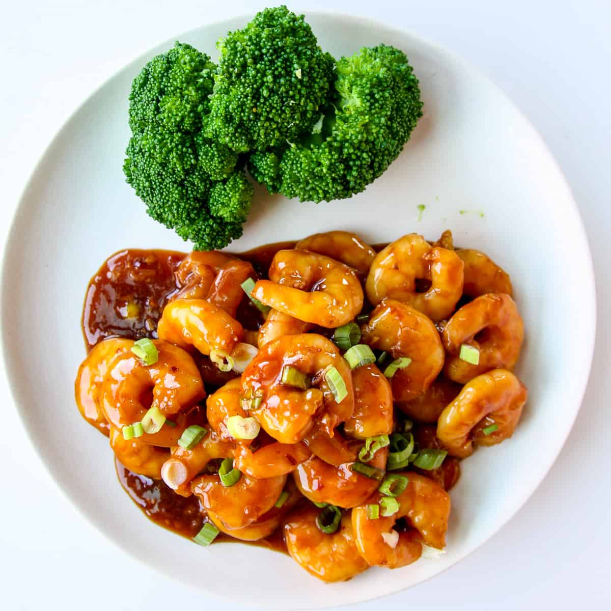 A plate of General Tso Shrimp on a white plate with a side of broccoli.