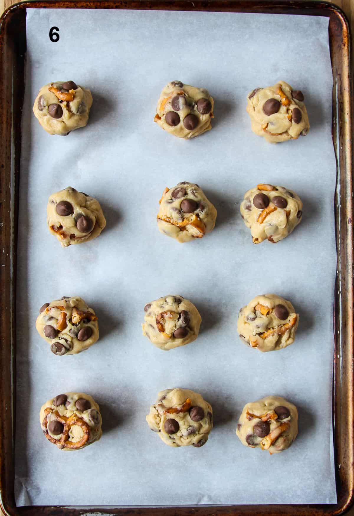 Cookie dough balls on a parchment paper lined baking sheet.