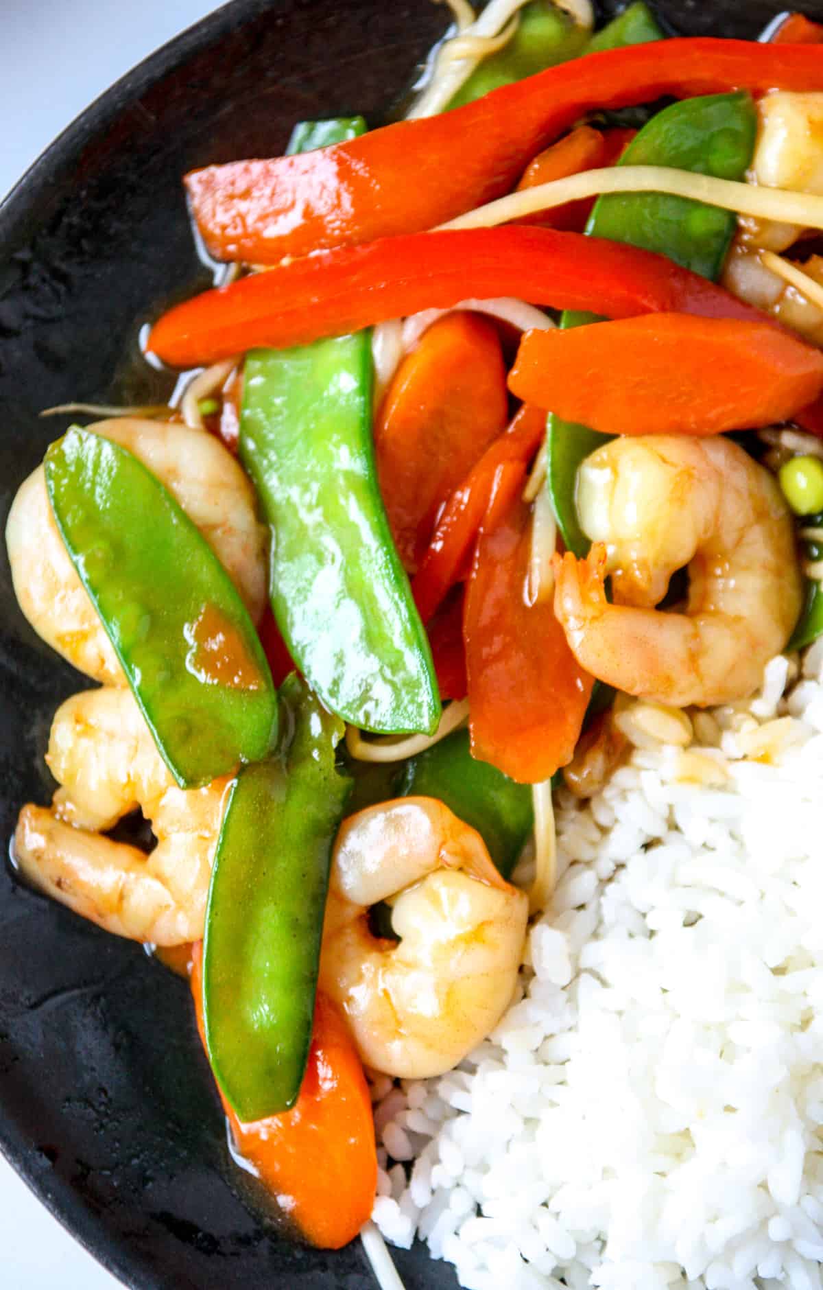 A close up of shrimp chop suey on a plate with some rice.