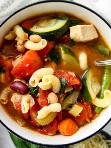 Chicken minestrone soup in a white bowl.