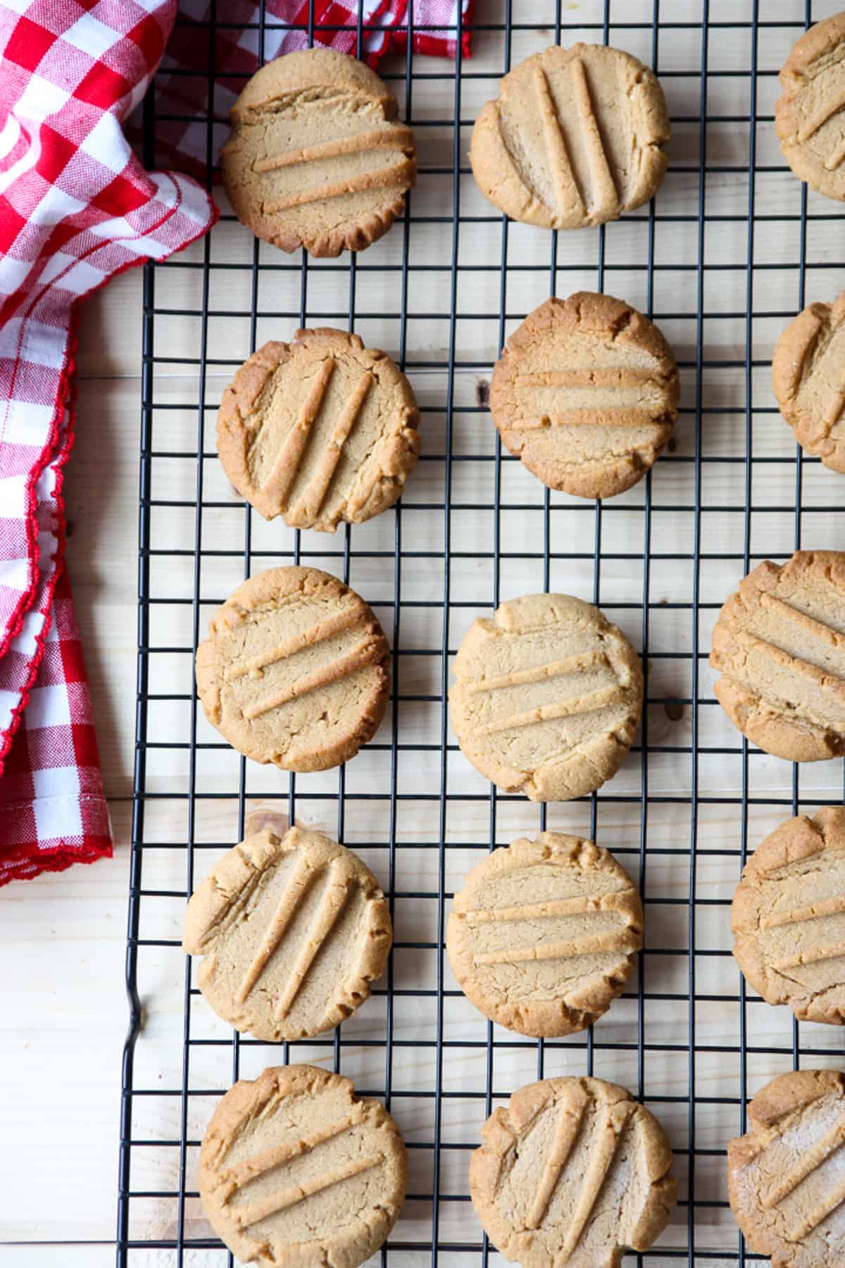 A dozen peanut butter cookies cooling on a wire rack.