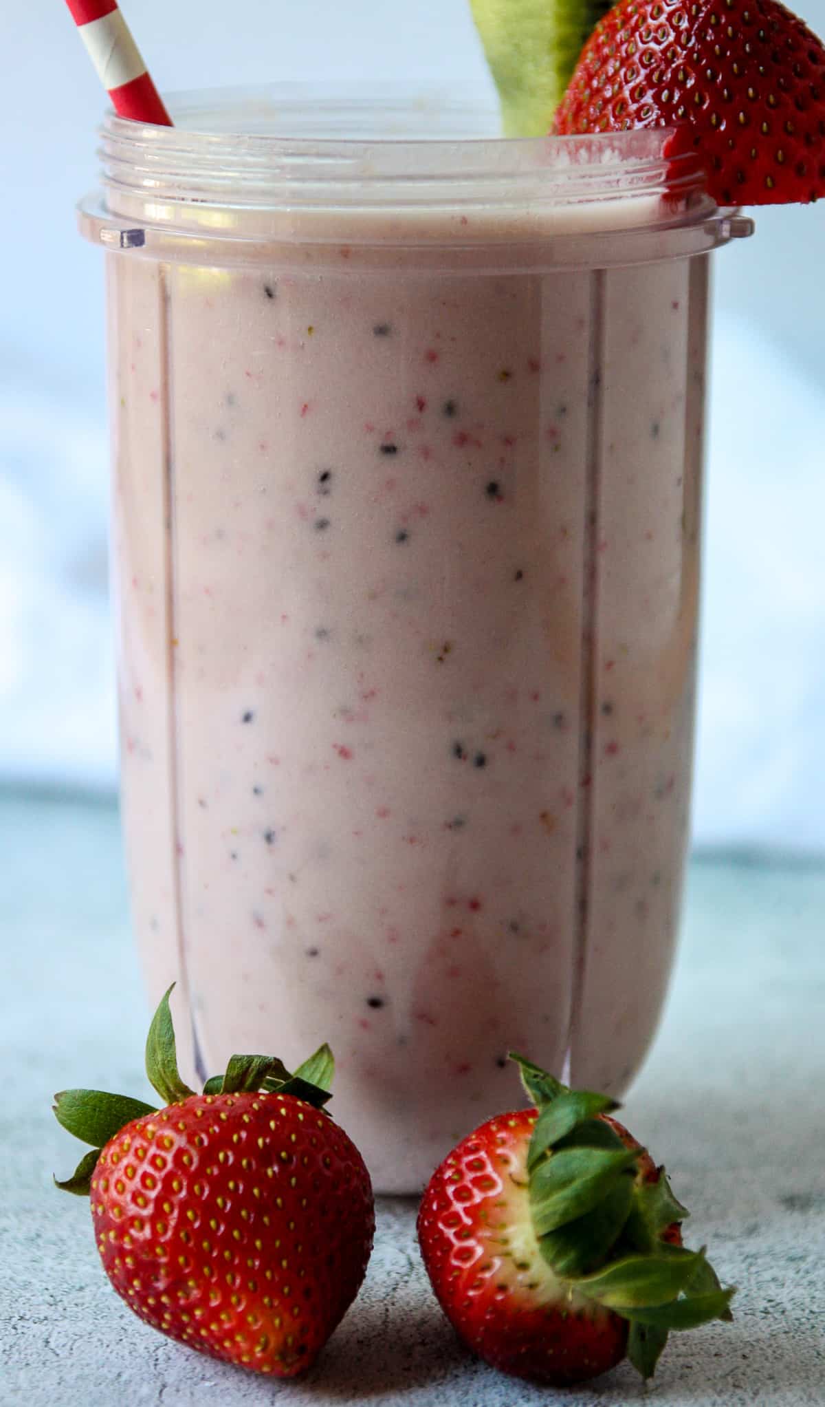 Pink colored kiwi quencher tropical smoothie in a tall glass.